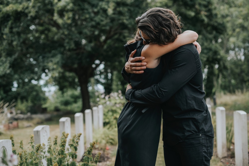 couple comforting each other at the graveyard