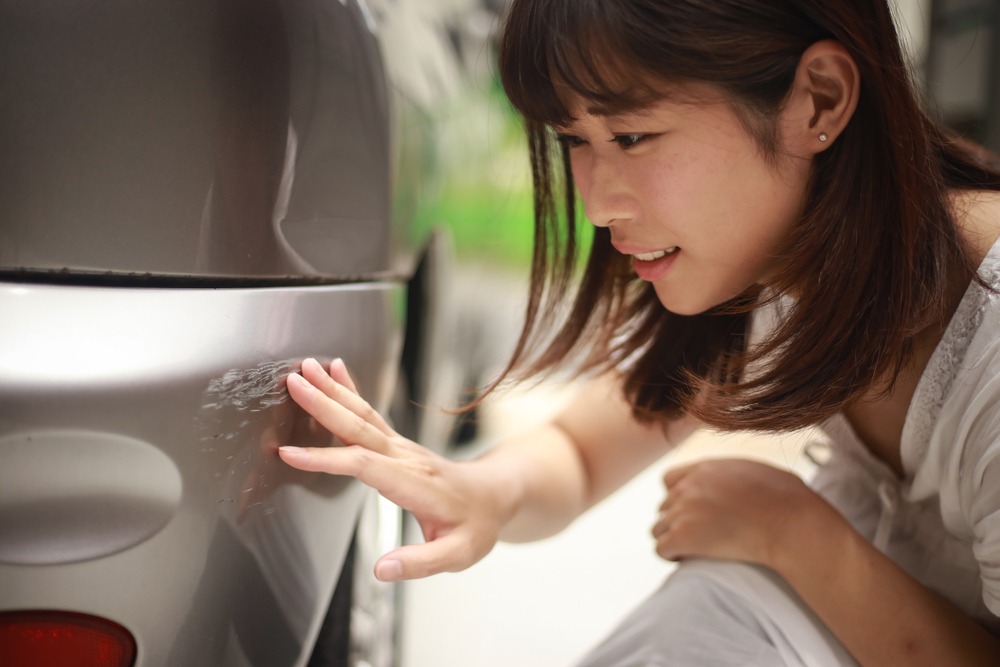 woman checking out damage to her car