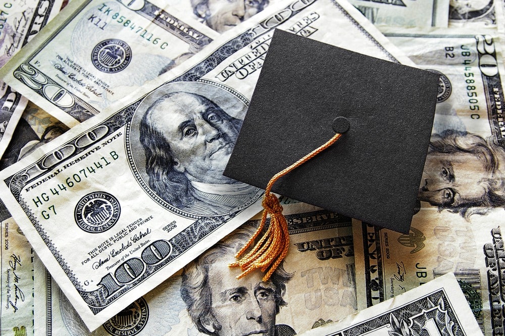 graduation cap on hundred-dollar bills