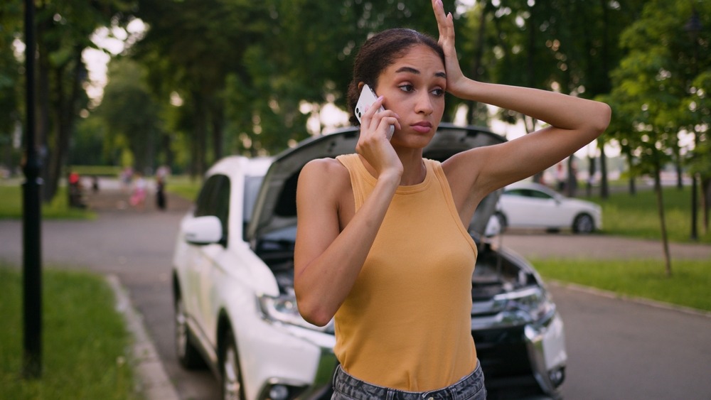 A young woman standing by her car after an accident. A lawyer can explain how long a car accident stays on your record in SC.