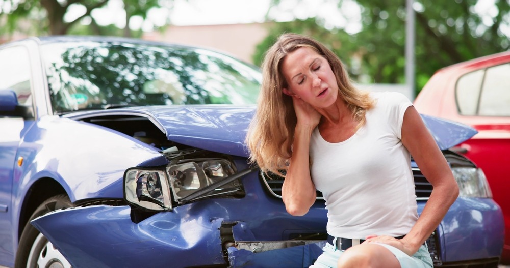 Person holding their neck after a car accident and concerned about the average cost of medical bills in the aftermath of this incident