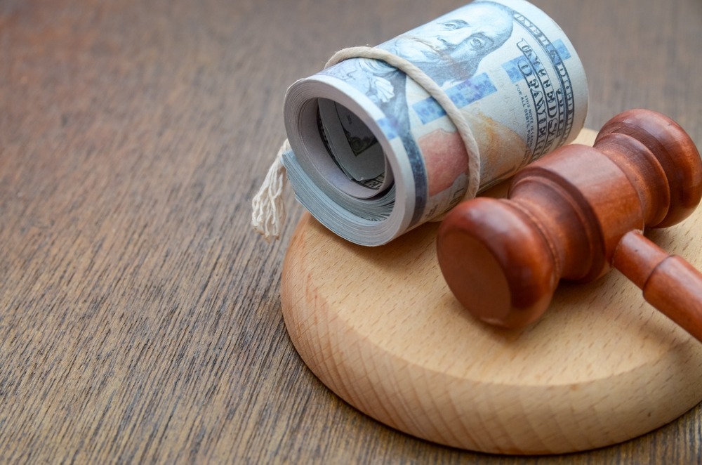 A judge’s gavel lying next to a roll of cash. Learn about the average dog bite settlement amount.