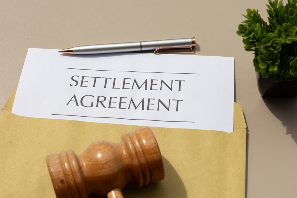 A piece of paper with “Settlement Agreement” written on it, with someone nearby wondering whether car accident settlements are taxable in South Carolina