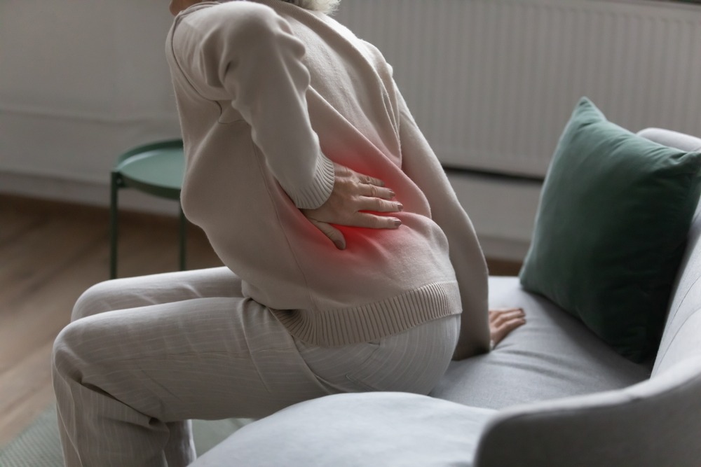 A woman experiences lower back pain linked to fibromyalgia, which can qualify for Disability under certain circumstances.