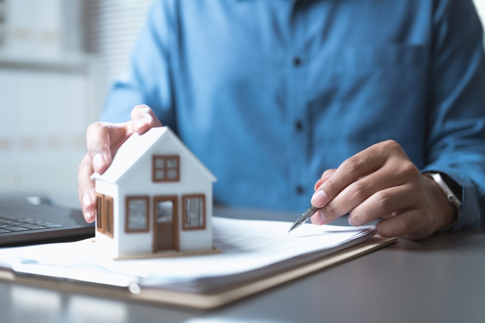 A man signing documents while holding a toy house. How long after bankruptcy can I get an FHA loan?