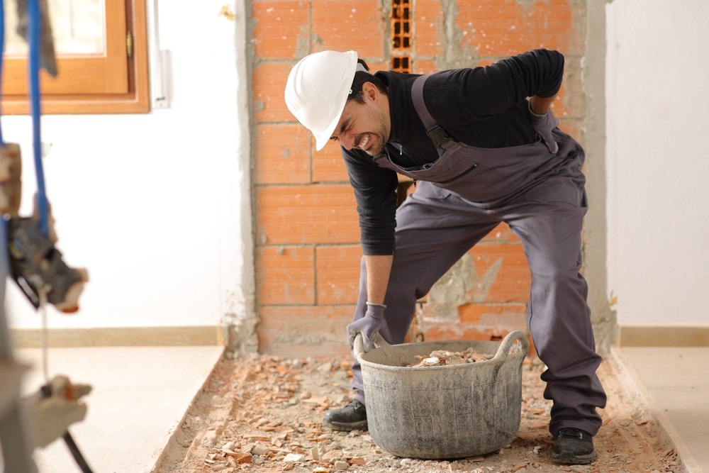 An injured construction worker, holding his back. How do I apply for workers’ compensation in NC?