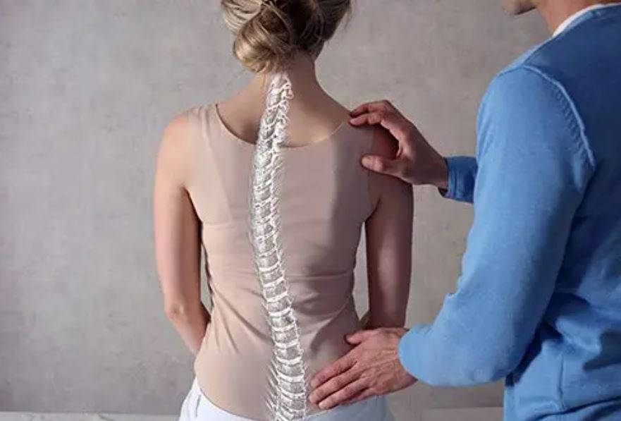 A woman with scoliosis with her doctor. An attorney can explain if scoliosis qualifies for disability.